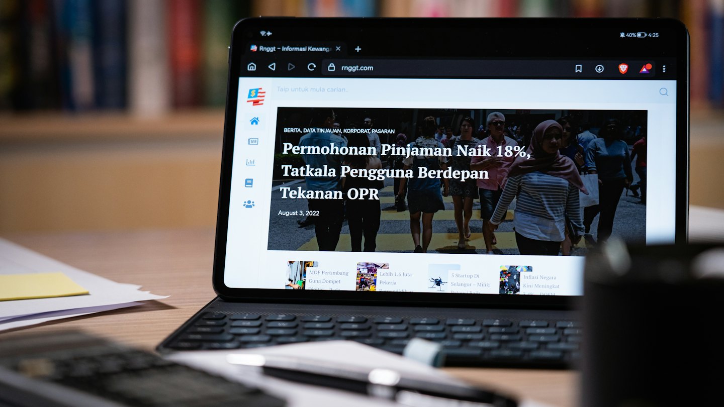 Bir klavyenin üzerinde finans haberlerini gösteren tablet.